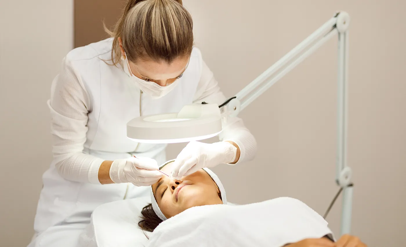 Dermatologist checking the patients skin for lesions with a tool.