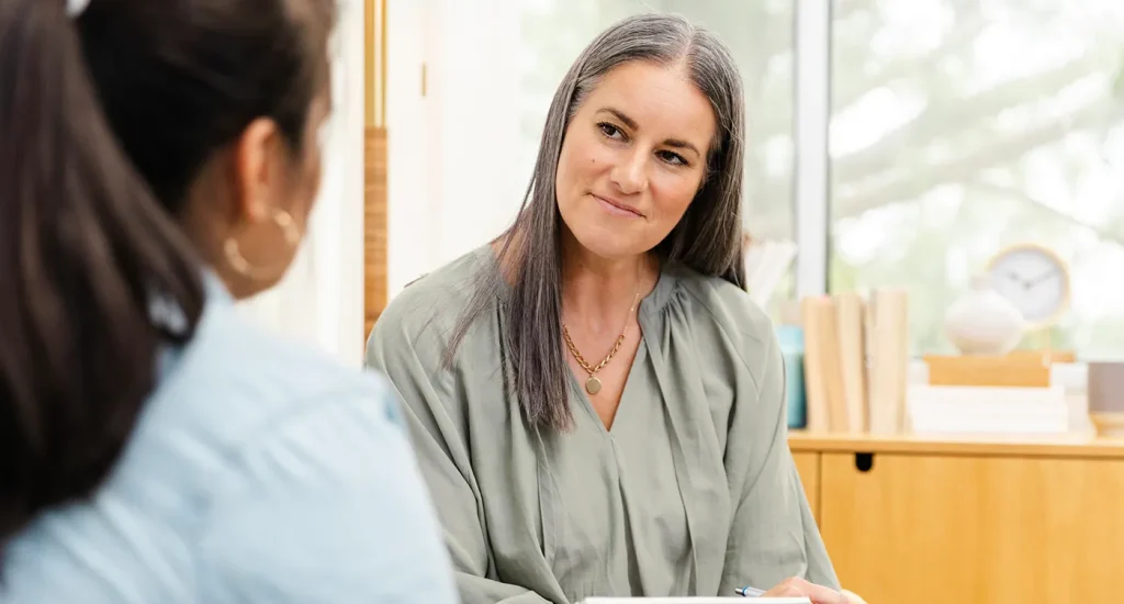 Attentive therapist speaks to a patient in her office.
