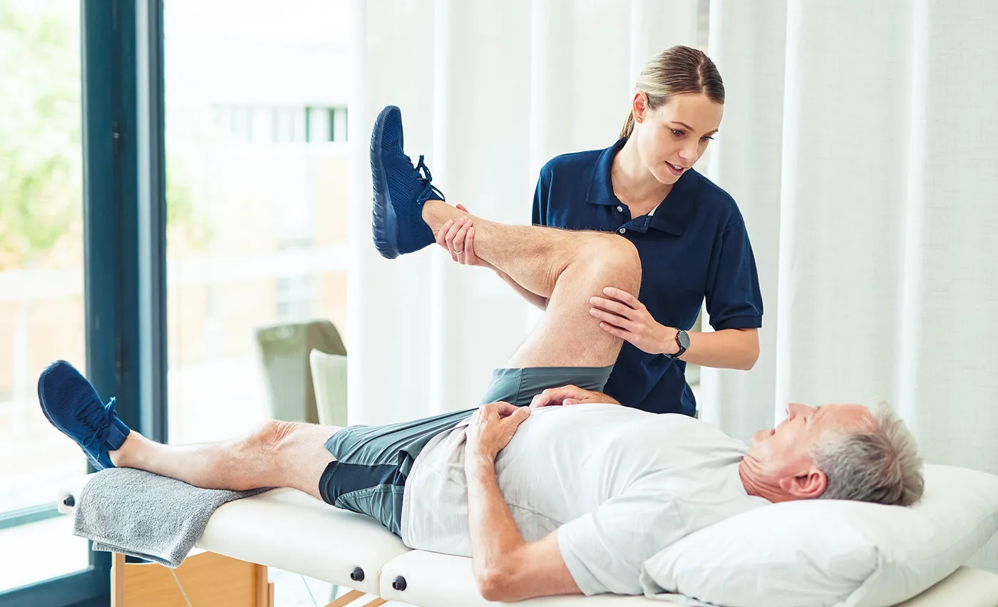 Orthopedic specialist bending patients leg on table.