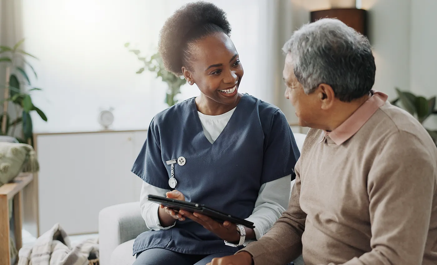 Senior care specialist with an elderly patient sitting on a bed.